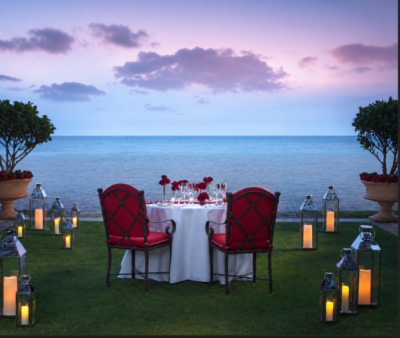 Private beachfront dinner table set by the ocean at sunset at Acqualina