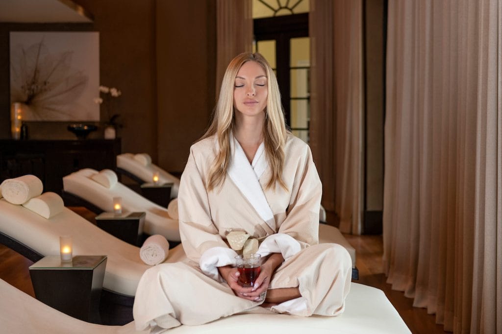 Woman Meditating at Acqualina Spa's Relaxation Lounge with Tea