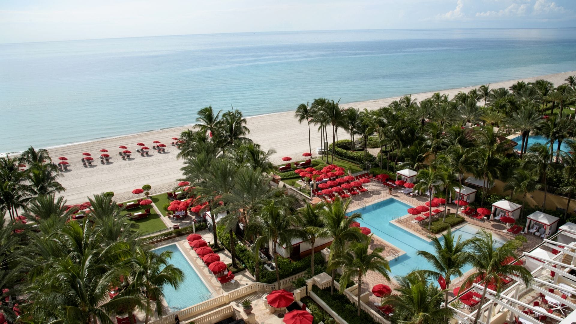 aerial view of luxury beachfront resort with pools and palm trees