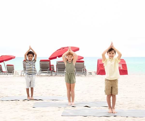 children practicing yoga on the beach