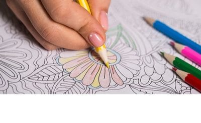 person coloring floral pattern with colored pencils