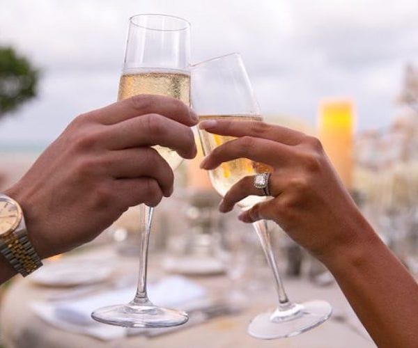 two people clinking champagne glasses at a romantic dinner